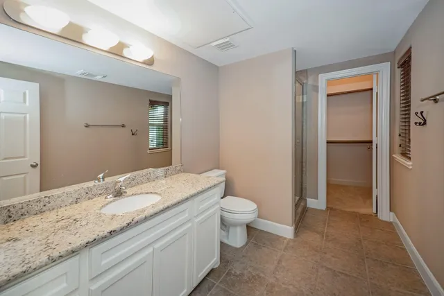 a bathroom with a granite countertop sink a toilet and a mirror