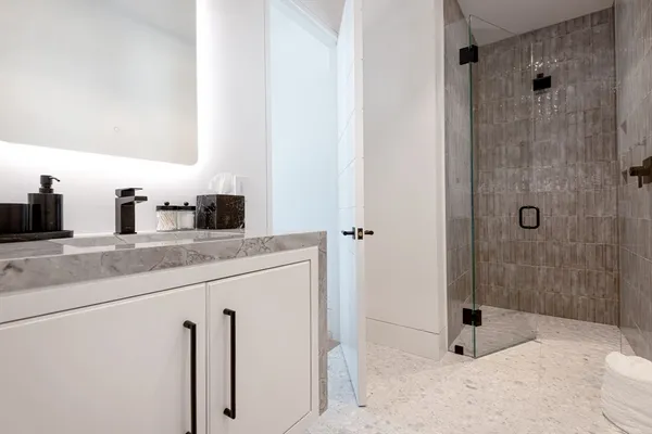 a bathroom with a granite countertop sink a mirror and shower