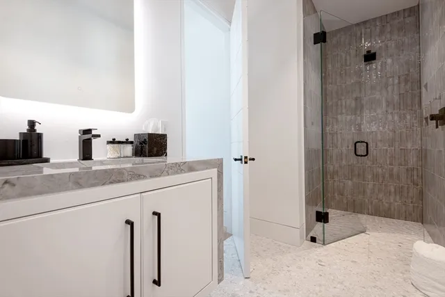a bathroom with a granite countertop sink a mirror and shower