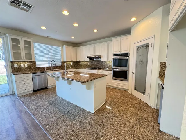 a large kitchen with stainless steel appliances granite countertop a stove top oven a sink and dishwasher