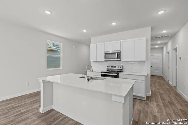 a kitchen with a sink a stove a refrigerator cabinets and wooden floor