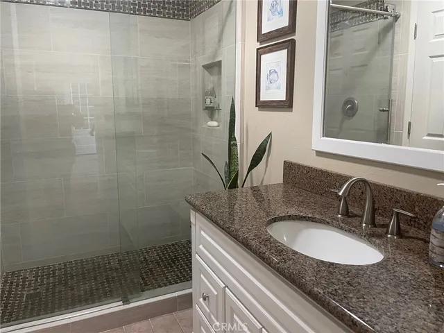 a bathroom with a granite countertop sink a mirror and shower