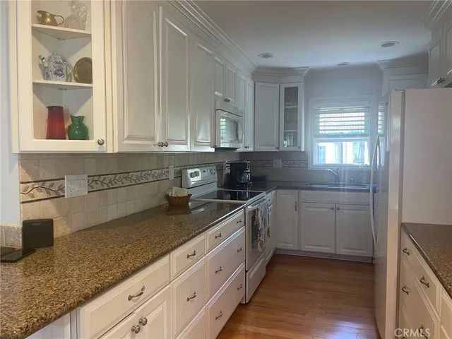 a kitchen with granite countertop white cabinets and white appliances