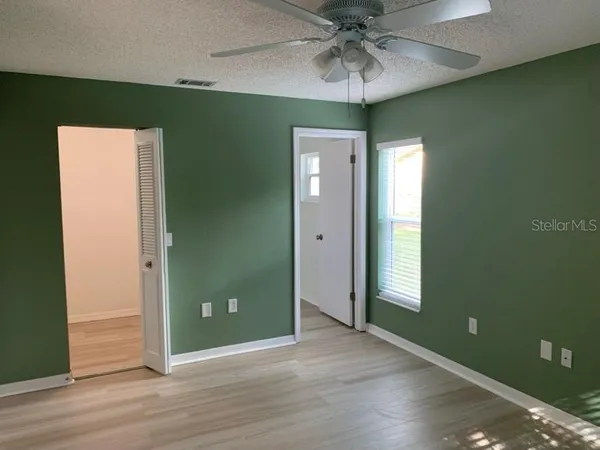 an empty room with wooden floor and fan