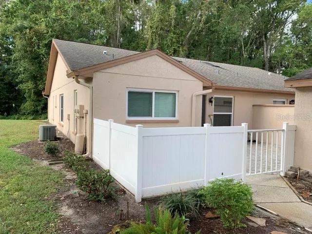 a view of a white house with a small yard and large trees