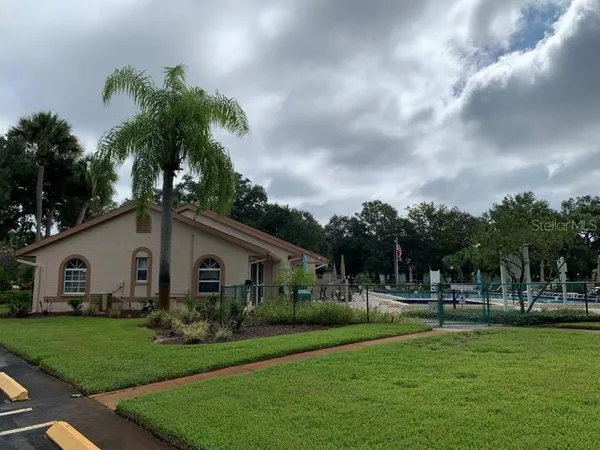 a view of a white house with a big yard and potted plants