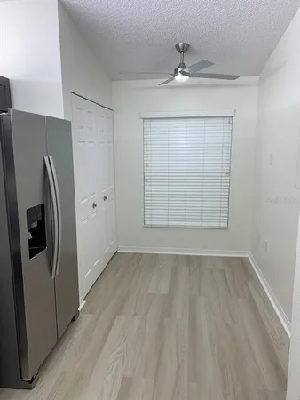 an empty room with wooden floor and a refrigerator