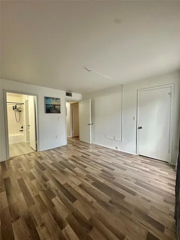a view of an empty room with closet and wooden floor
