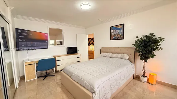 a bedroom with a bed a couch and a flat screen tv