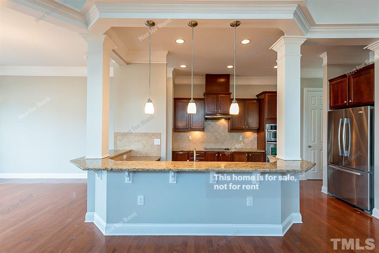 1225 Chapanoke Road Raleigh, NC 27603 - Photo 2 of 27 a kitchen with kitchen island granite countertop wooden cabinets and a refrigerator