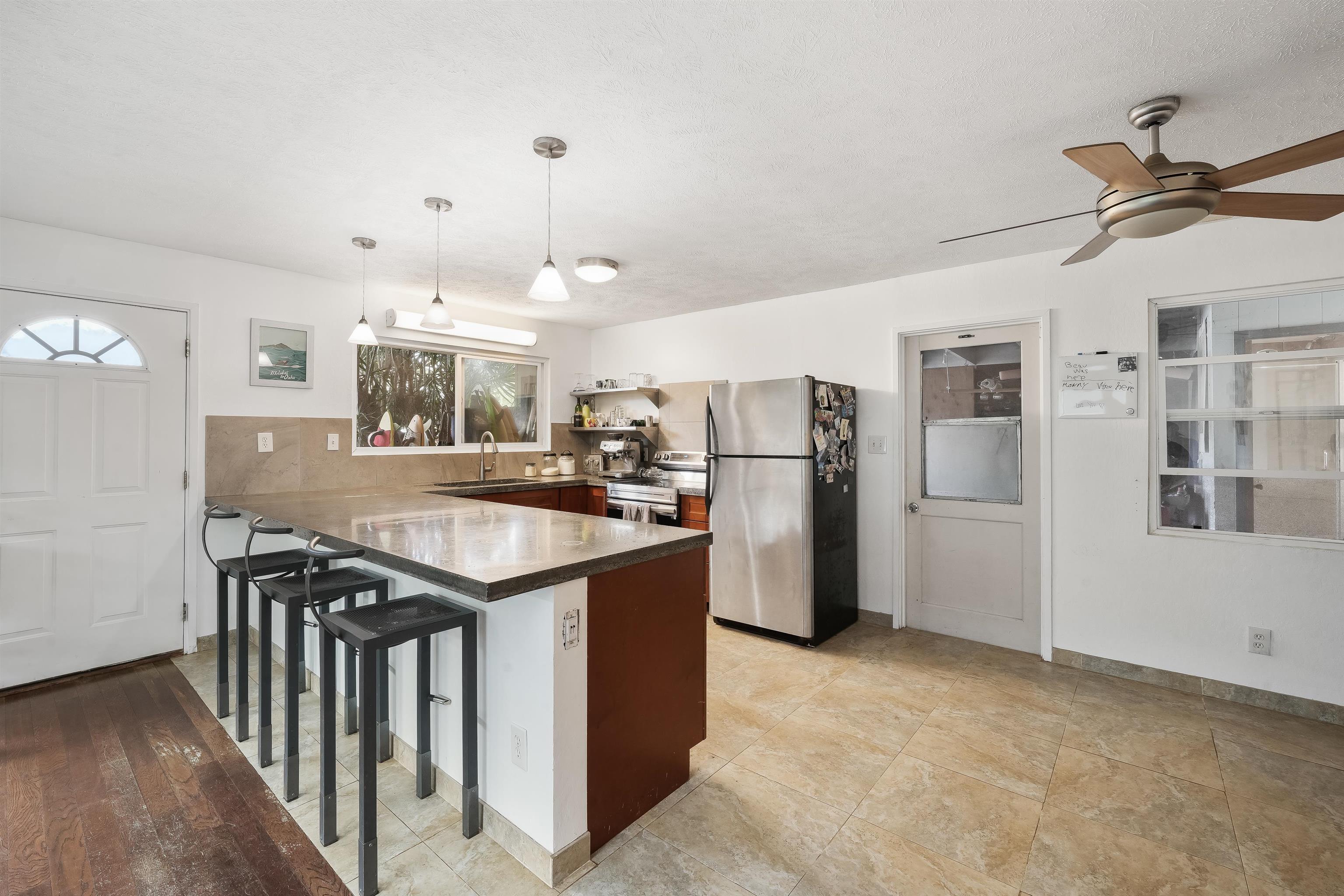2889 West Lelehuna Place Haiku, HI 96708 - Photo 11 of 32 a kitchen with stainless steel appliances granite countertop a refrigerator a stove a sink dishwasher and a refrigerator with wooden floor