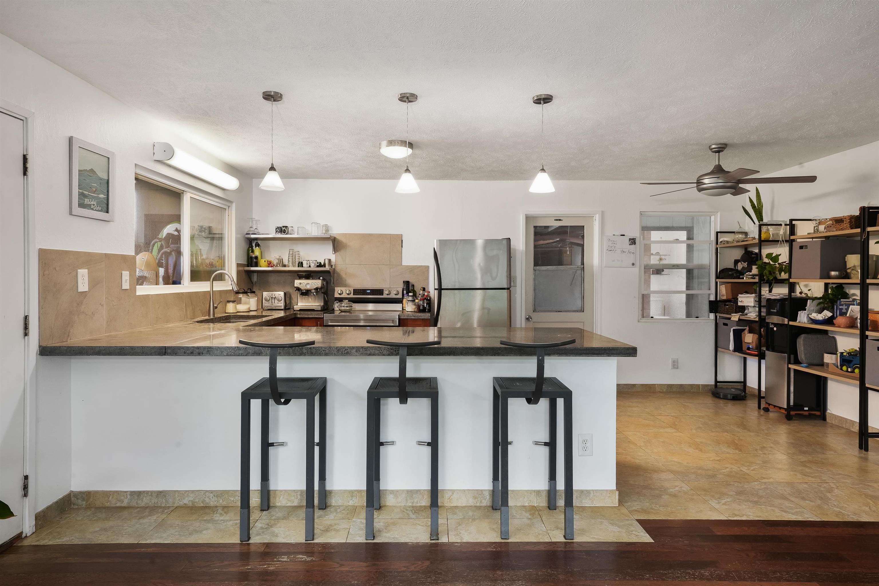 2889 West Lelehuna Place Haiku, HI 96708 - Photo 12 of 32 a kitchen with stainless steel appliances granite countertop a table chairs refrigerator and sink