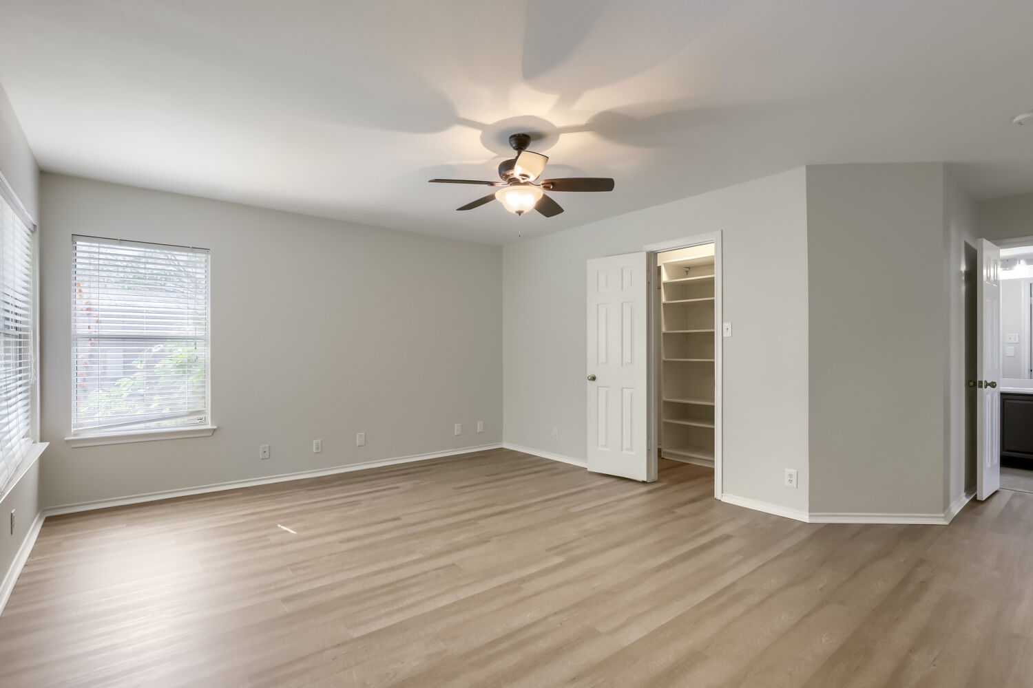 7411 Pusch Ridge Loop Austin, TX 78749 - Photo 17 of 29 an empty room with wooden floor chandelier fan and windows