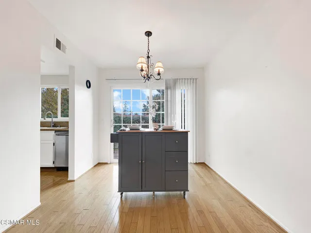 a living room with kitchen island granite countertop wooden floor and a refrigerator