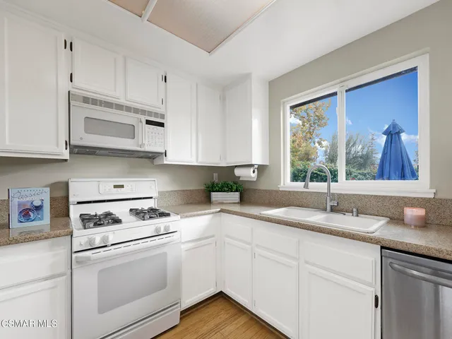 a kitchen with granite countertop white cabinets white appliances and a sink