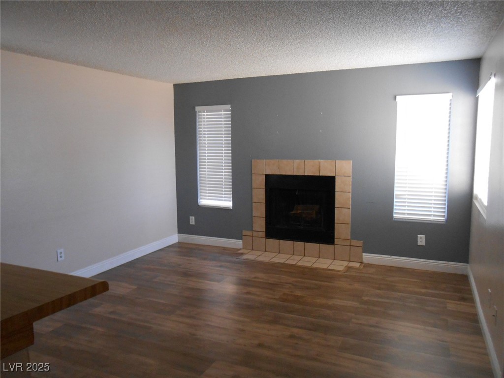 4720 Krissylouise Way, Unit B Las Vegas, NV 89121 - Photo 2 of 14 Unfurnished living room featuring a textured ceiling, wood finished floors, healthy amount of natural light, and a tile fireplace