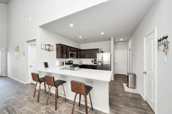 a kitchen with stainless steel appliances a sink dishwasher a refrigerator a stove top oven a sink with island and chairs