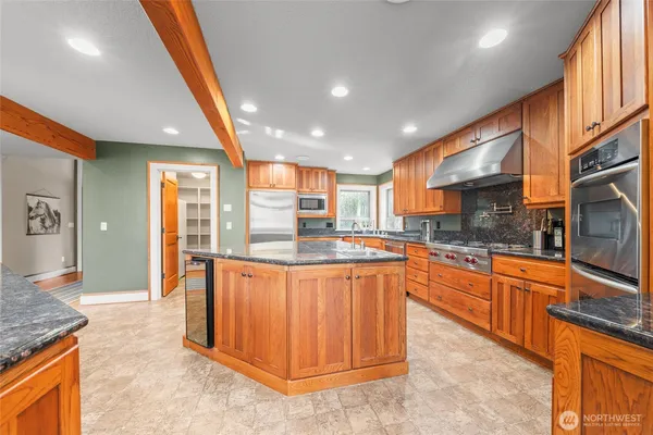 a large kitchen with stainless steel appliances granite countertop a large counter top and a stove top oven