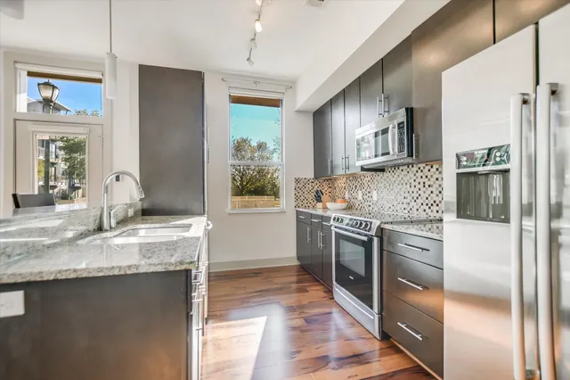 a kitchen with stainless steel appliances granite countertop a refrigerator a stove and a sink