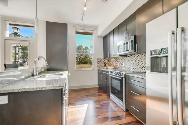 a kitchen with stainless steel appliances granite countertop a refrigerator a stove and a sink