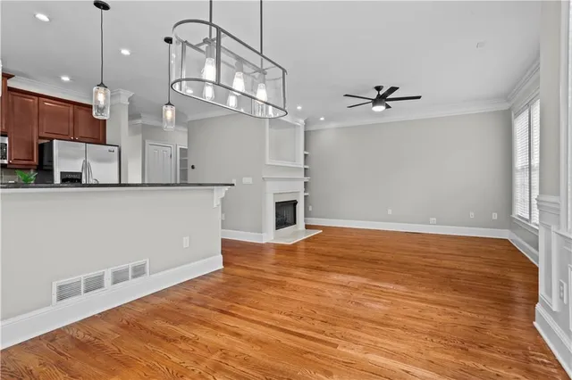 a view of an empty room with wooden floor fireplace and a window