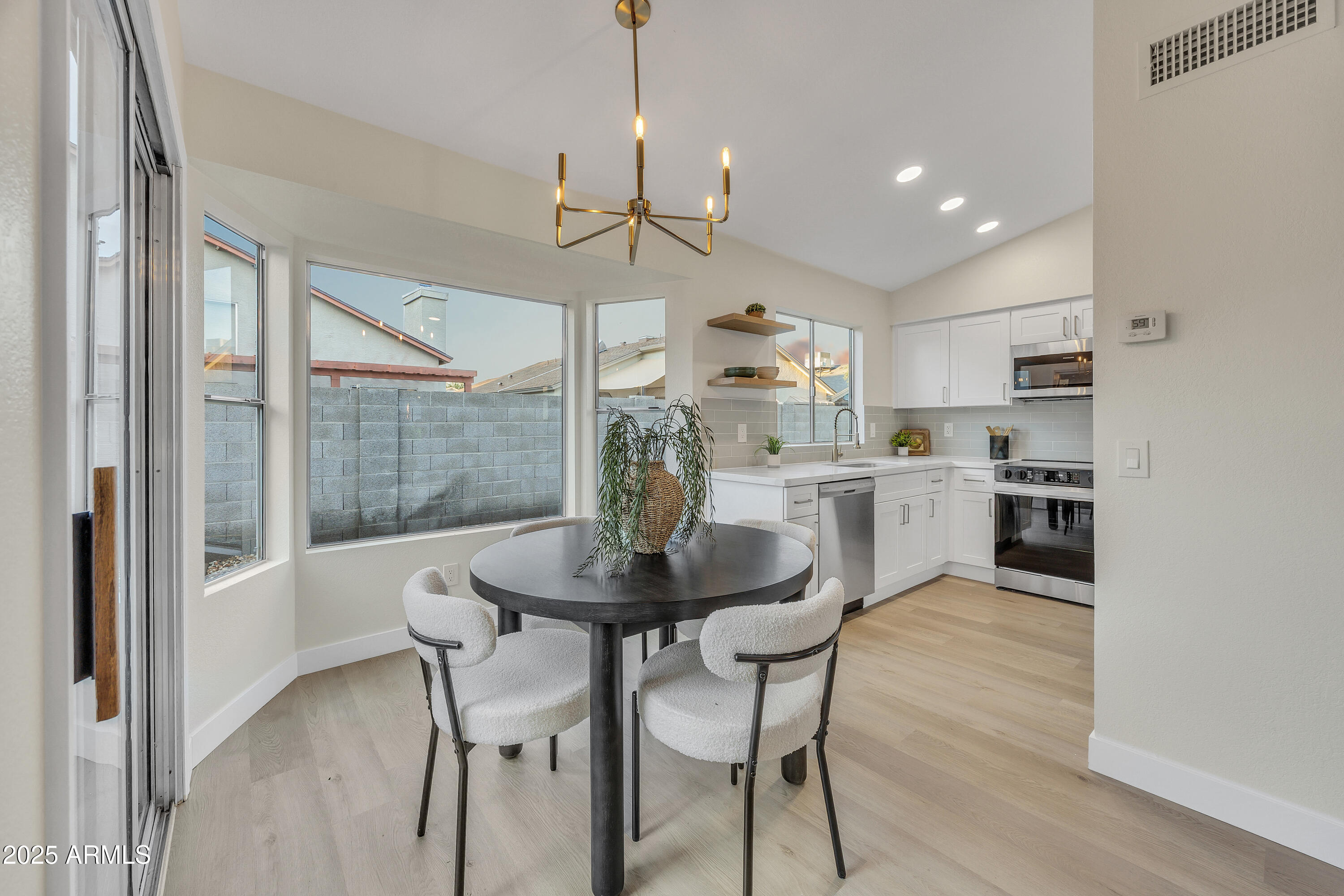 8830 West St John Road Peoria, AZ 85382 - Photo 9 of 25 a kitchen with stainless steel appliances a dining table chairs and wooden floor