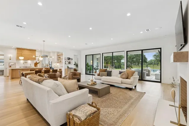a living room with furniture large windows and a view of kitchen