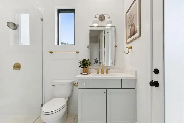 a bathroom with a sink a toilet and shower a mirror
