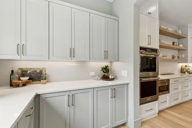 a kitchen with stainless steel appliances granite countertop a sink dishwasher stove and white cabinets with wooden floor