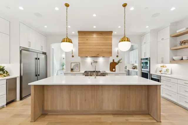 a large kitchen with kitchen island a counter space a sink stainless steel appliances and cabinets