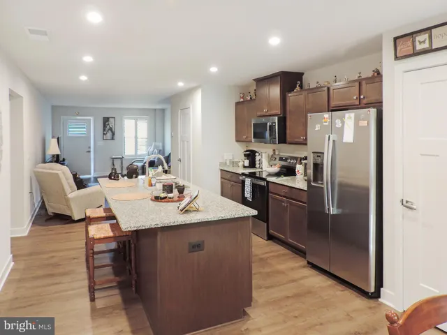 a kitchen with stainless steel appliances kitchen island granite countertop a refrigerator a stove a sink a dining table and chairs