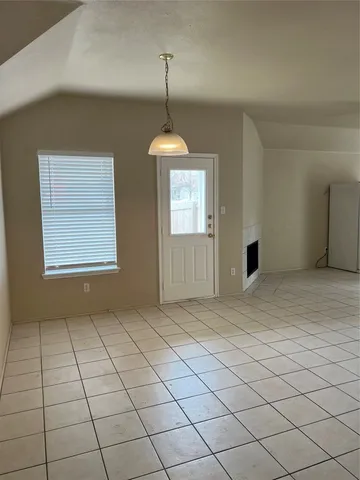 a view of an empty room with window and chandelier fan