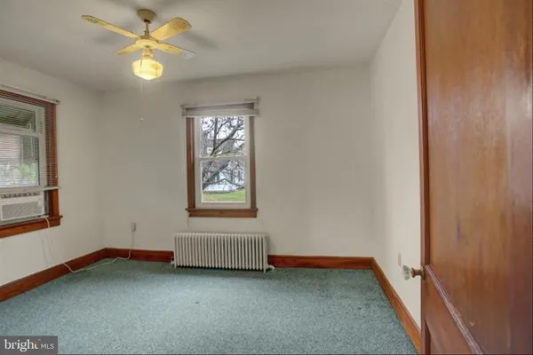 an empty room with windows and fan