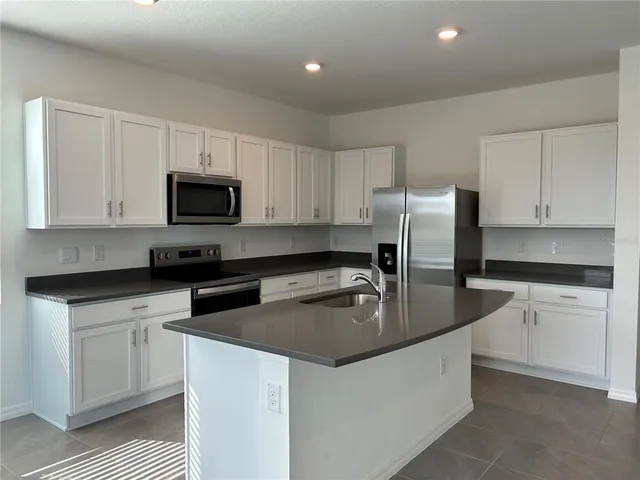 a kitchen with kitchen island a sink stove top oven and refrigerator