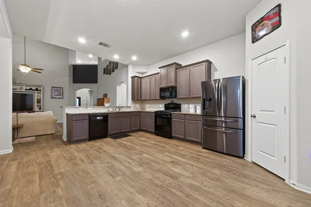 a kitchen with stainless steel appliances kitchen island granite countertop a refrigerator and a sink