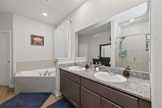 a bathroom with a granite countertop tub sink and mirror