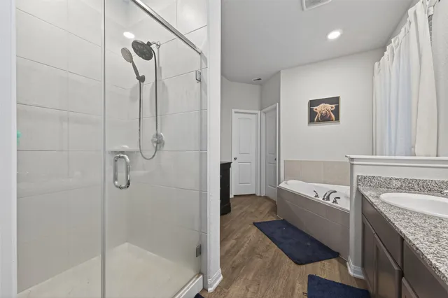 a bathroom with a granite countertop sink a mirror bathtub and shower