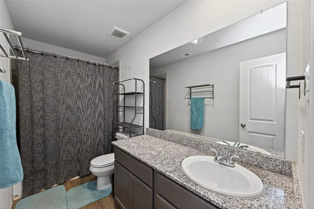 a bathroom with a granite countertop sink toilet and shower