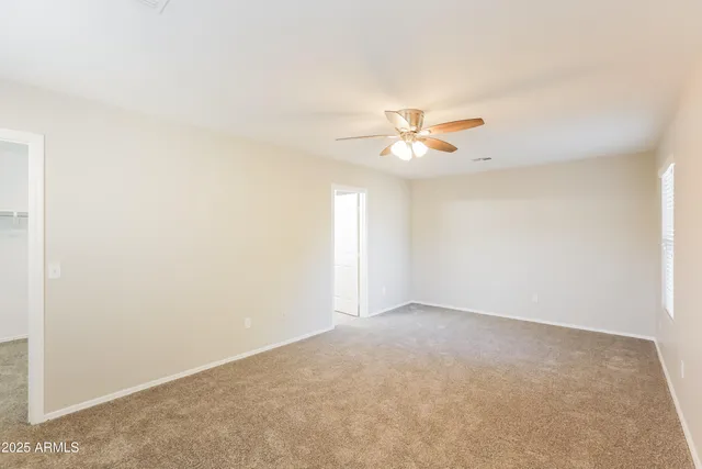 an empty room with a window and a ceiling fan