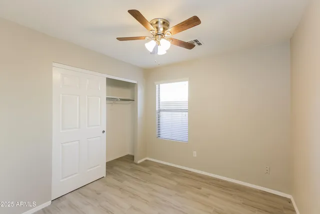 an empty room with chandelier fan and windows