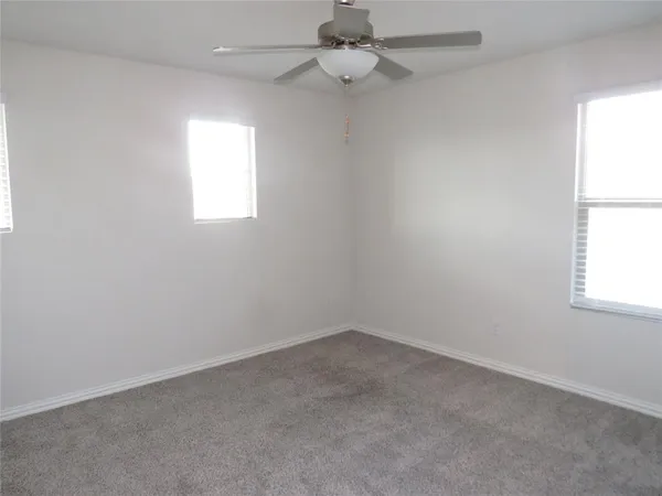 an empty room with a window and ceiling fan
