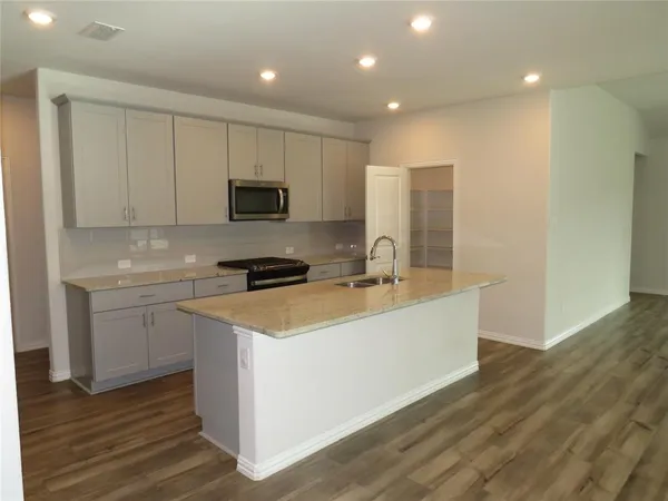 a kitchen with a sink cabinets and wooden floor
