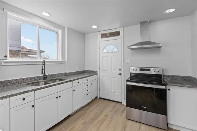 a kitchen with granite countertop a sink a stove and cabinets