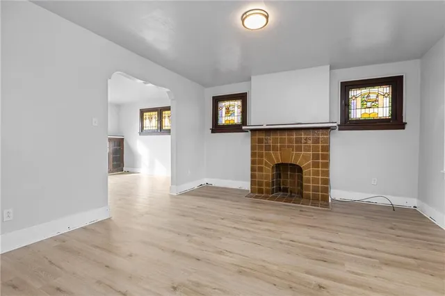 an empty room with wooden floor fireplace and windows