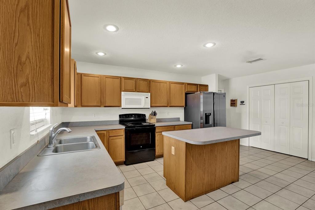 8240 Neda Street Spring Hill, FL 34606 - Photo 12 of 53 a kitchen with stainless steel appliances granite countertop a sink stove and refrigerator