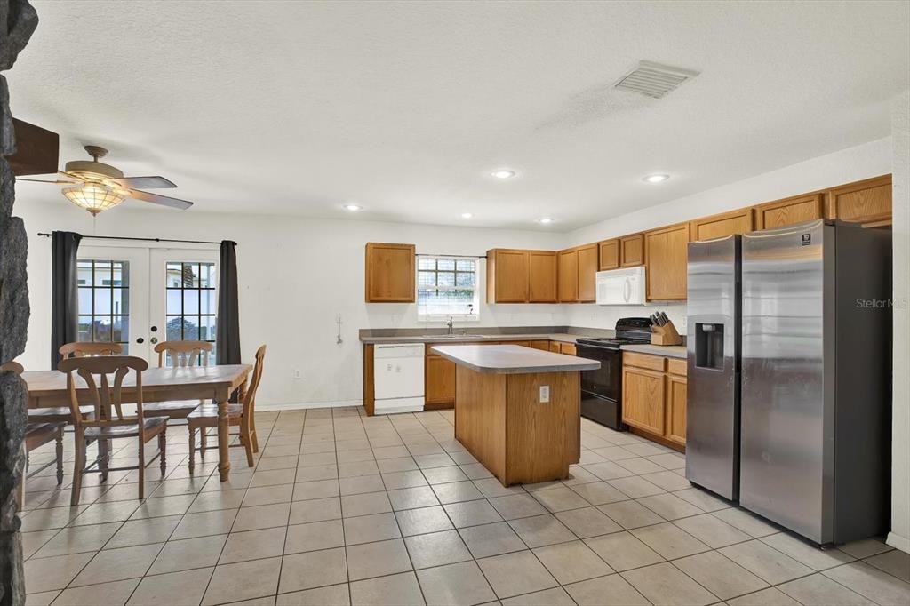 8240 Neda Street Spring Hill, FL 34606 - Photo 13 of 53 a kitchen with stainless steel appliances kitchen island granite countertop a table chairs and a refrigerator