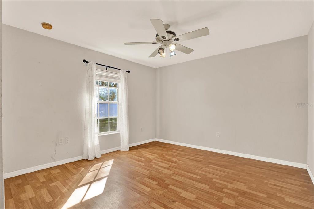 8240 Neda Street Spring Hill, FL 34606 - Photo 29 of 53 an empty room with wooden floor fan and windows