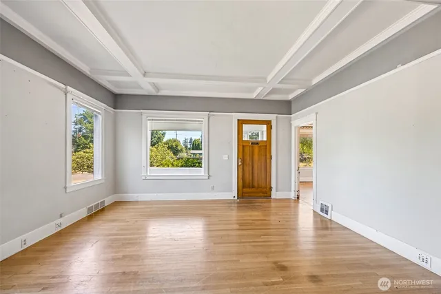 an empty room with wooden floor and windows