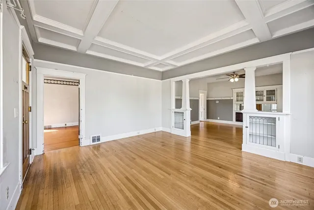 a view of empty room with wooden floor and kitchen view