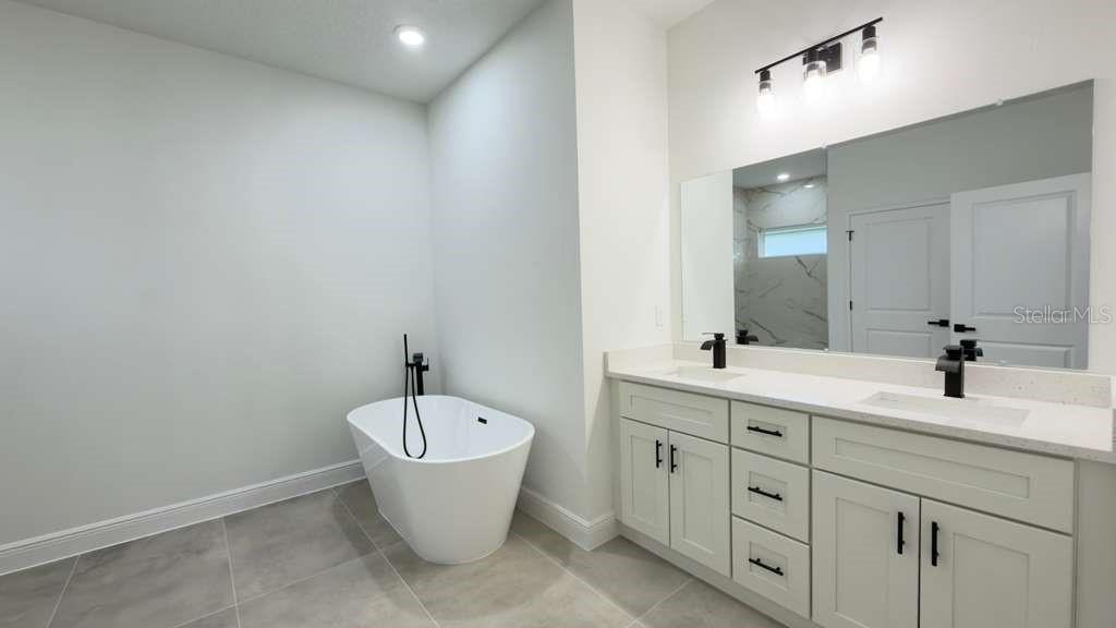 14905 Southwest 24th Circle Ocala, FL 34472 - Photo 17 of 24 a bathroom with a double vanity sink a mirror and a bathtub